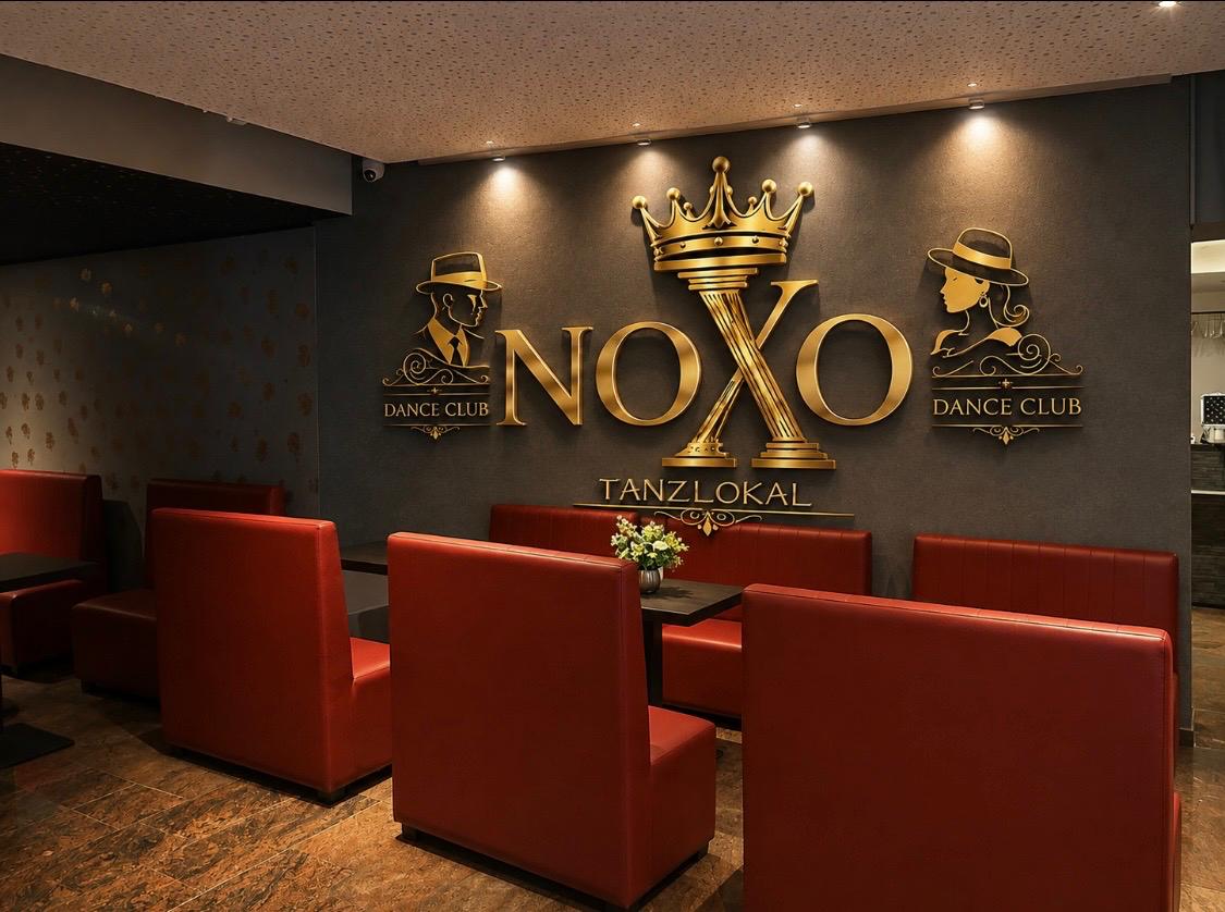 NOXO Lounge mit goldener Logo-Wand und roten Sitzbänken